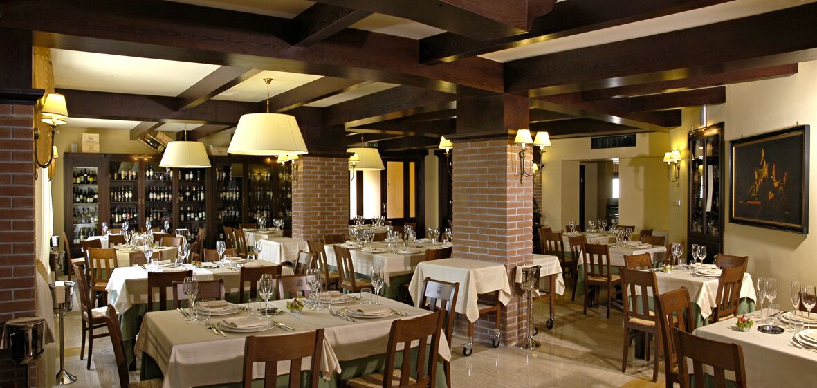 Un restaurante con varias mesas preparadas para comer, con paredes de ladrillo y vigas de madera.