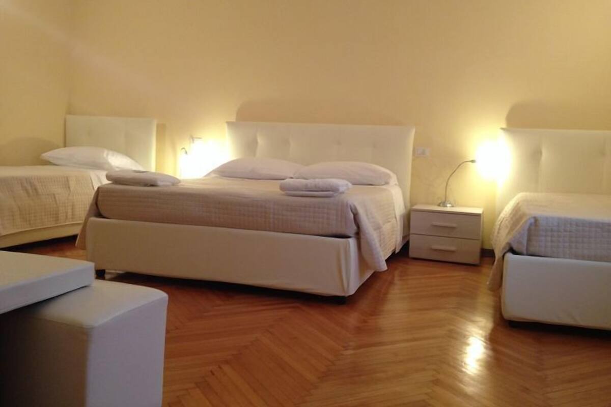 Una habitación de hotel con una cama grande, dos mesitas de noche y suelo de madera.