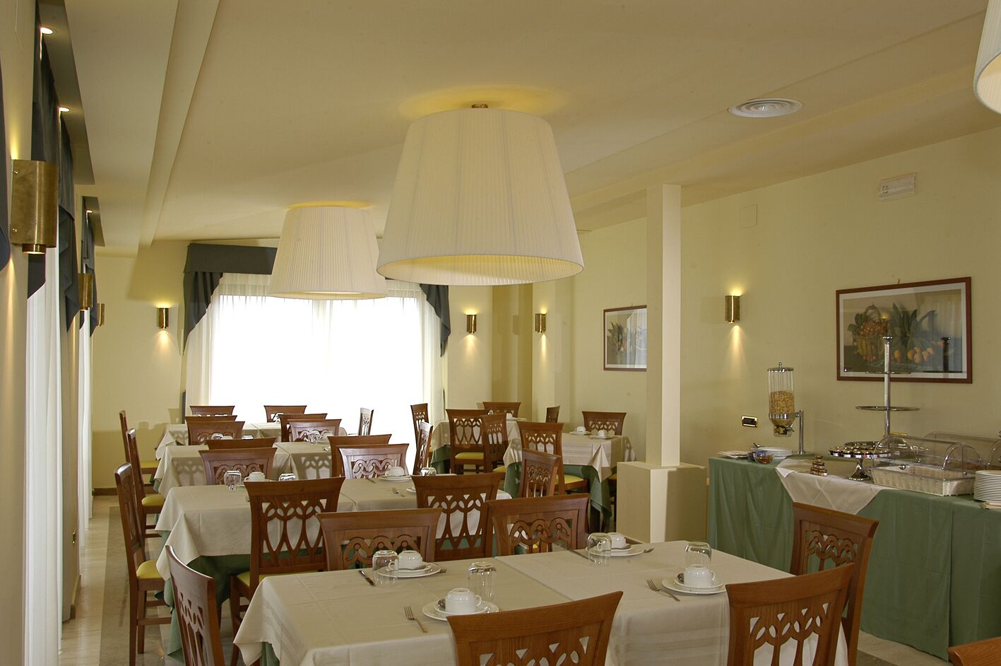 A dining area with tables set for service, chairs, and a buffet station.