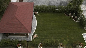 A building with a red roof, a well-maintained lawn, and potted plants.