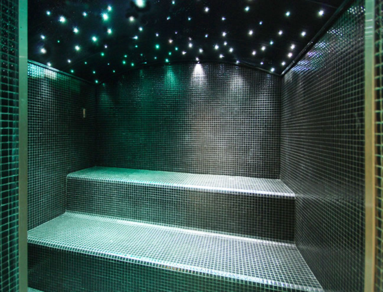 A tiled room with steps and a ceiling with small lights.