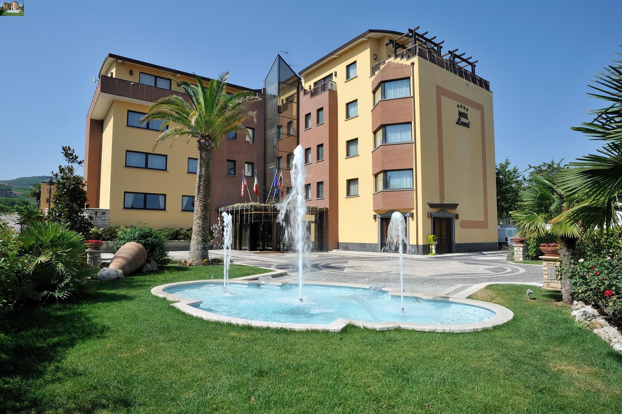 Ein Hotel mit Swimmingpool, Palmen und einer Springbrunnen.