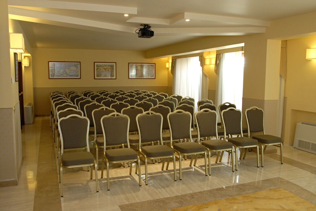 A conference room with rows of chairs, a projector, and framed artwork on the walls.