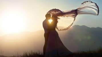A couple embracing with a heart-shaped silhouette against a sunset.