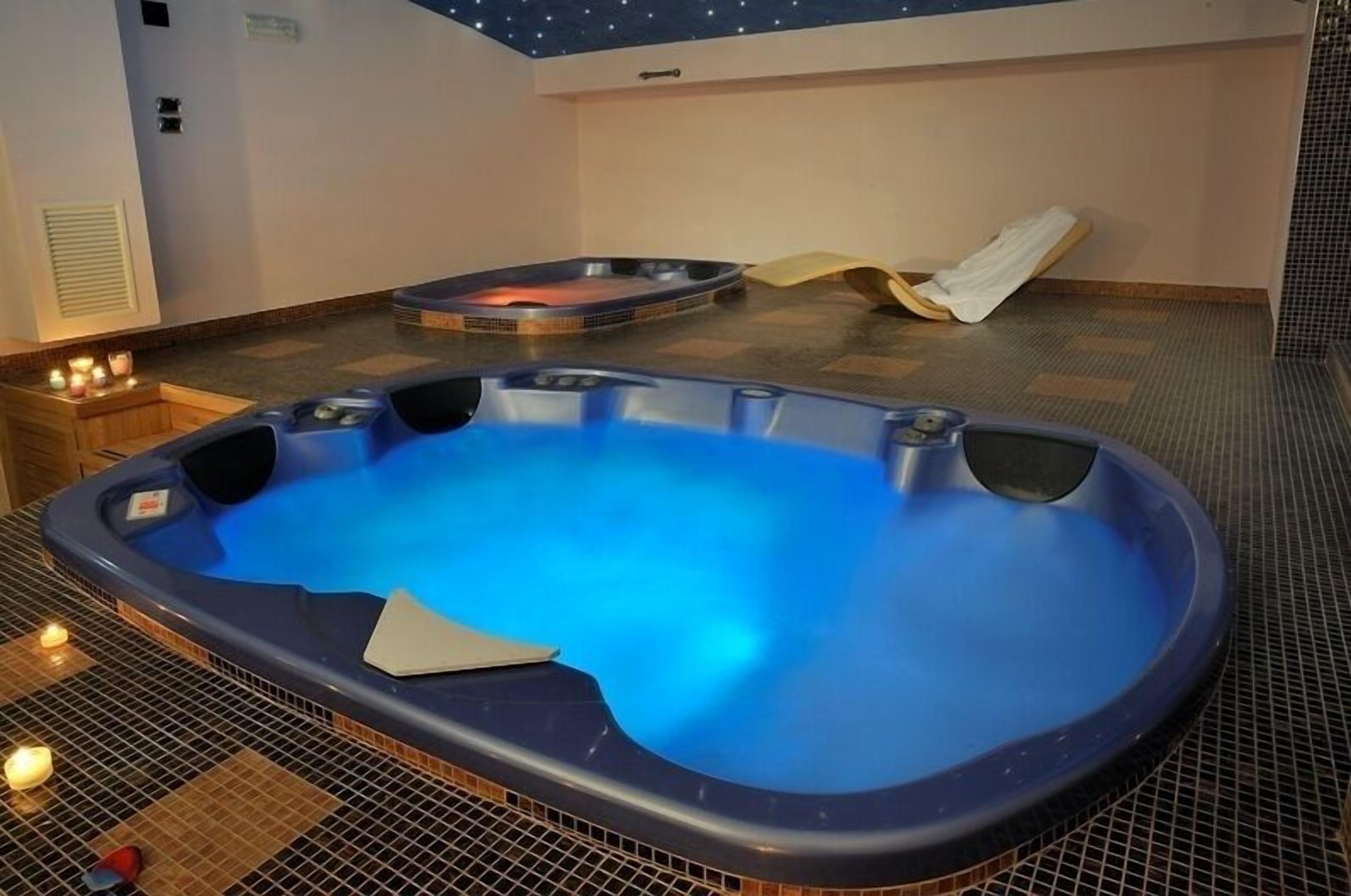 Un jacuzzi con interior azul, un jacuzzi más pequeño al fondo, y una toalla en el suelo.