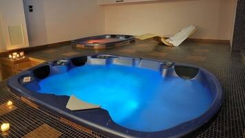 Un jacuzzi con interior azul, un jacuzzi más pequeño al fondo, y una toalla en el suelo.