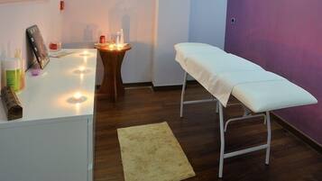 Een kamer met een witte bank, een klein tafeltje met kaarsen en een spiegel aan de muur.