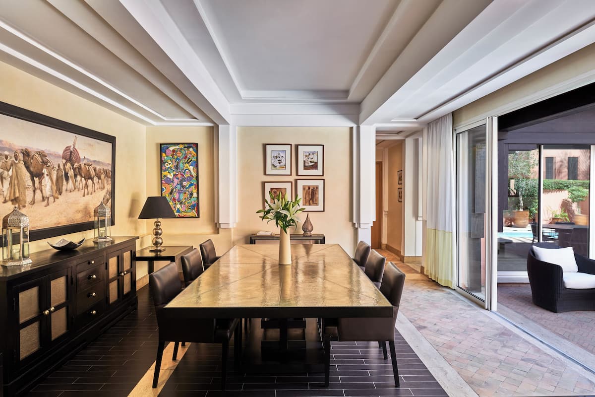 A dining area with a large table, chairs, a vase with flowers, and artwork on the walls.