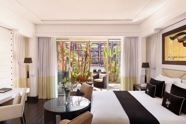 Una habitación de hotel con una cama grande, una mesa de comedor y vistas a una zona de piscina.