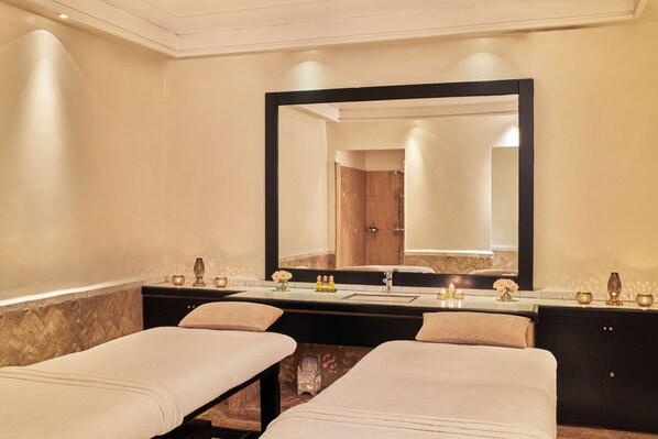 A hotel room with a large mirror, a vanity with a sink, and two massage tables. - Hôtel & Ryads Barrière Le Naoura (Marrakech)