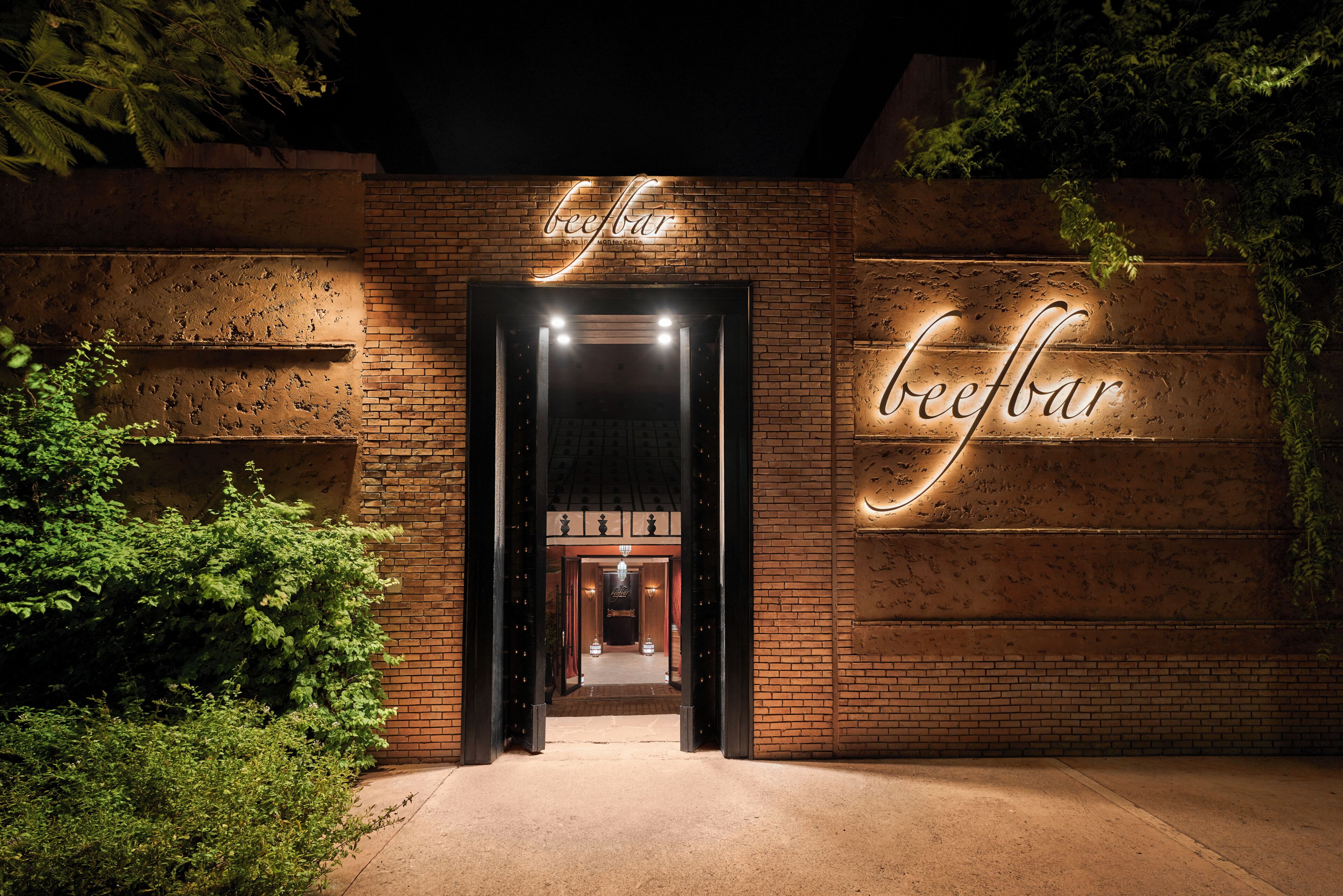 A brick building entrance with illuminated signage reading 'beefbar.'