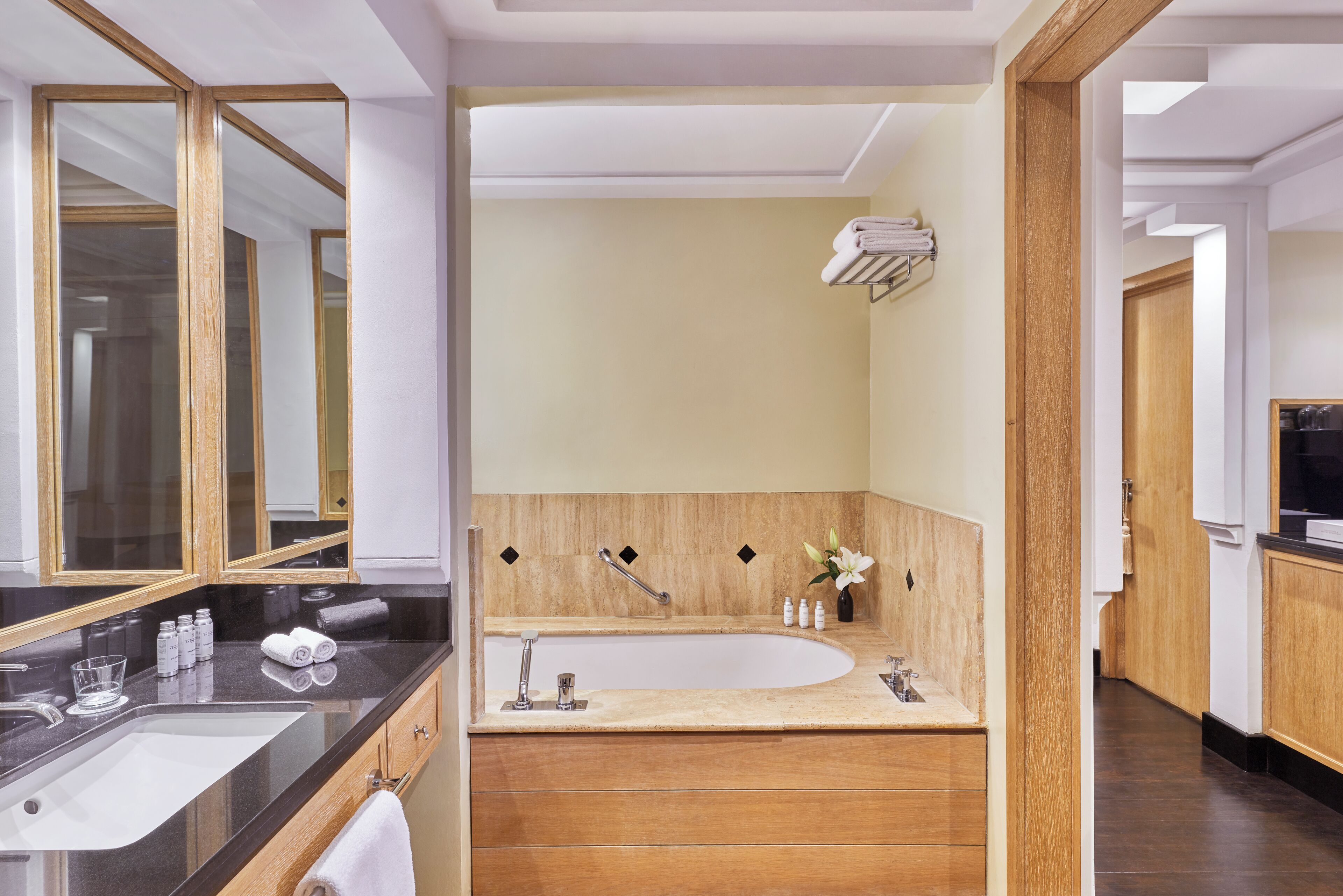 A modern bathroom with a large mirror, a bathtub, and a vanity with a sink.