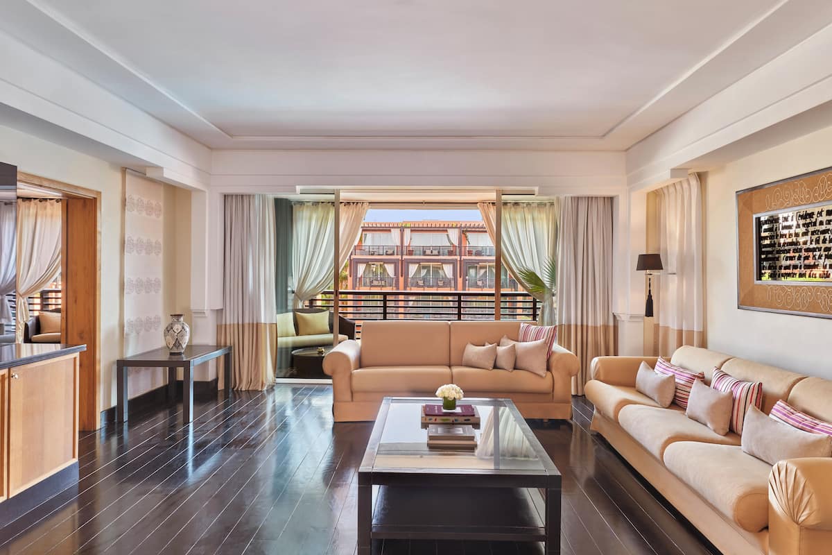 A spacious living room with a large sofa, a coffee table, and a view of a building through a large window.