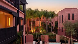 A courtyard with a pool, lounge chairs, and potted plants.