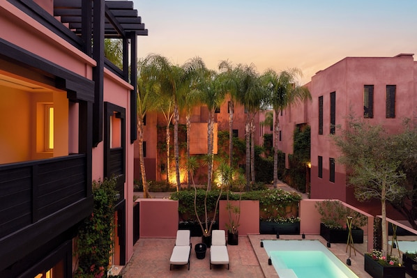 Une cour avec une piscine, des chaises longues et des plantes en pot.