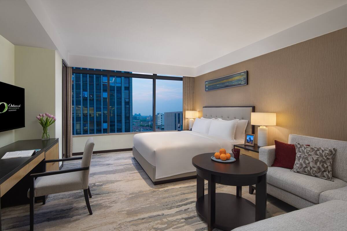 Een hotelkamer met een groot bed, een bureau, een stoel, een bank, een salontafel en een televisie.