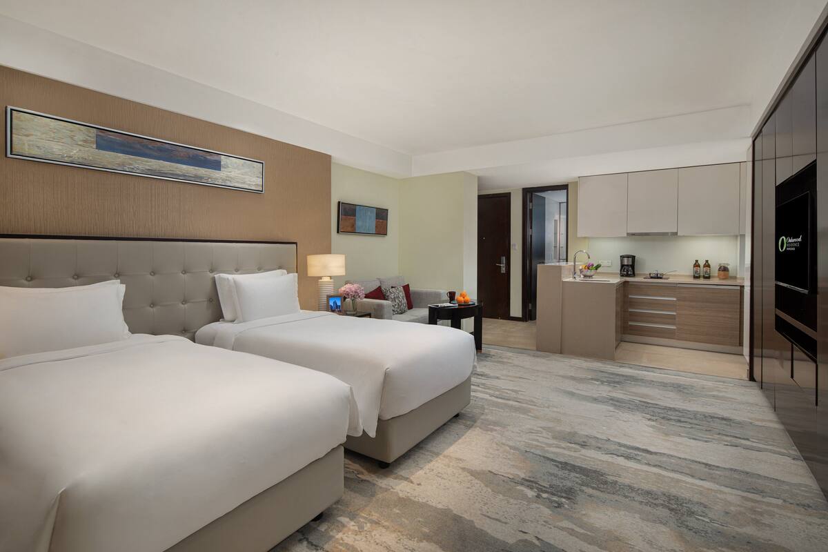 Een hotelkamer met twee bedden, een kitchenette en een badkamer.