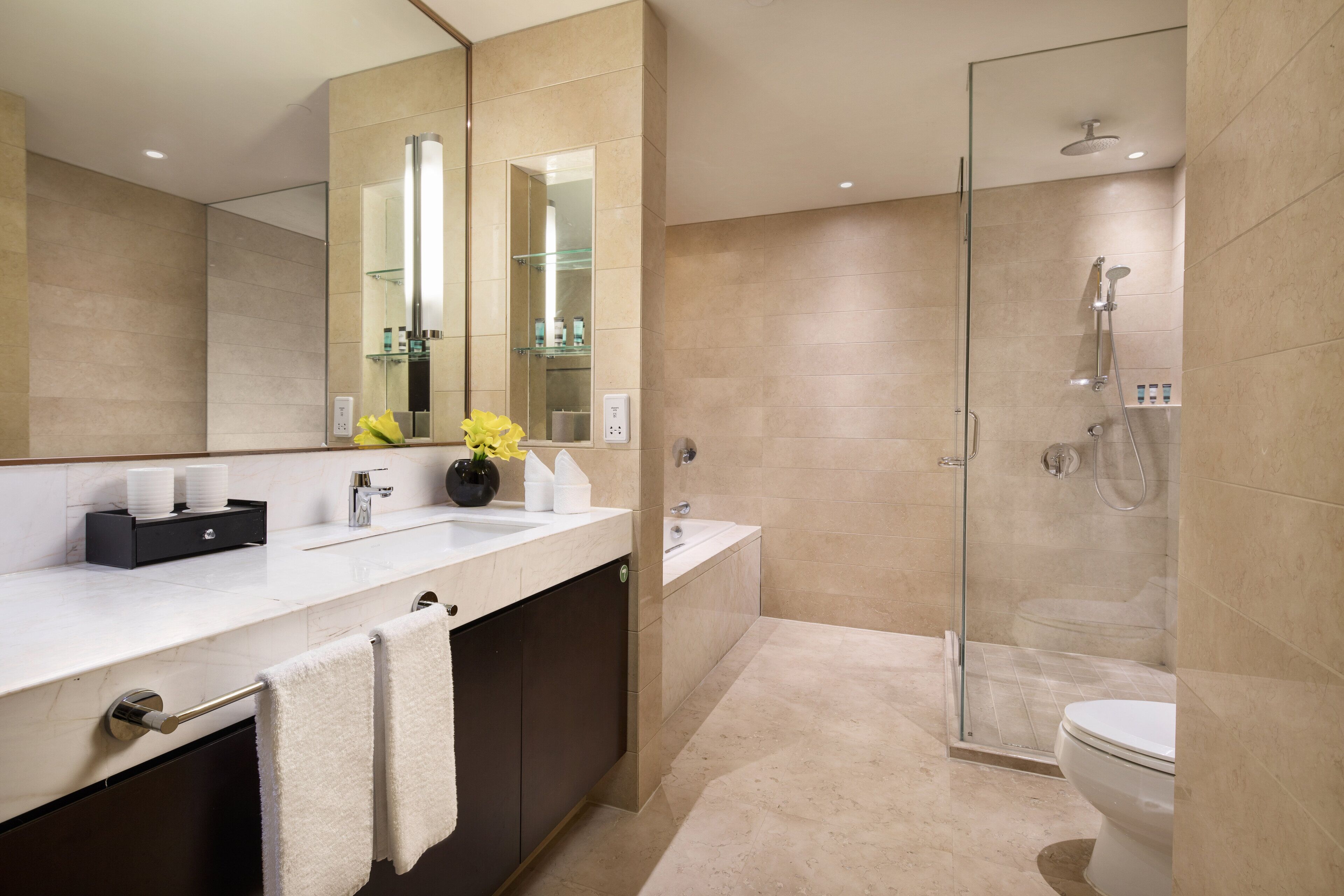 A modern bathroom with a large mirror, a glass shower enclosure, and a white sink.