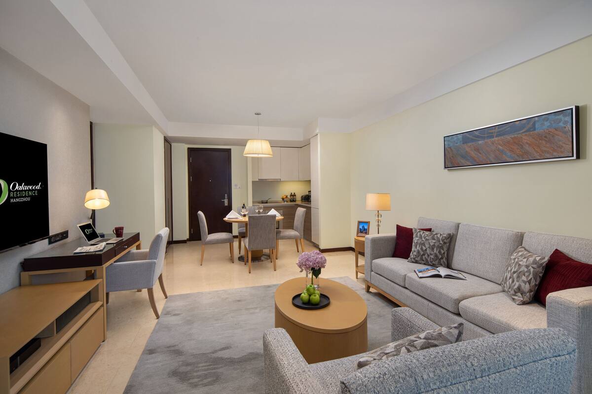 Een moderne hotelkamer met een zithoek, een eethoek en een kitchenette.