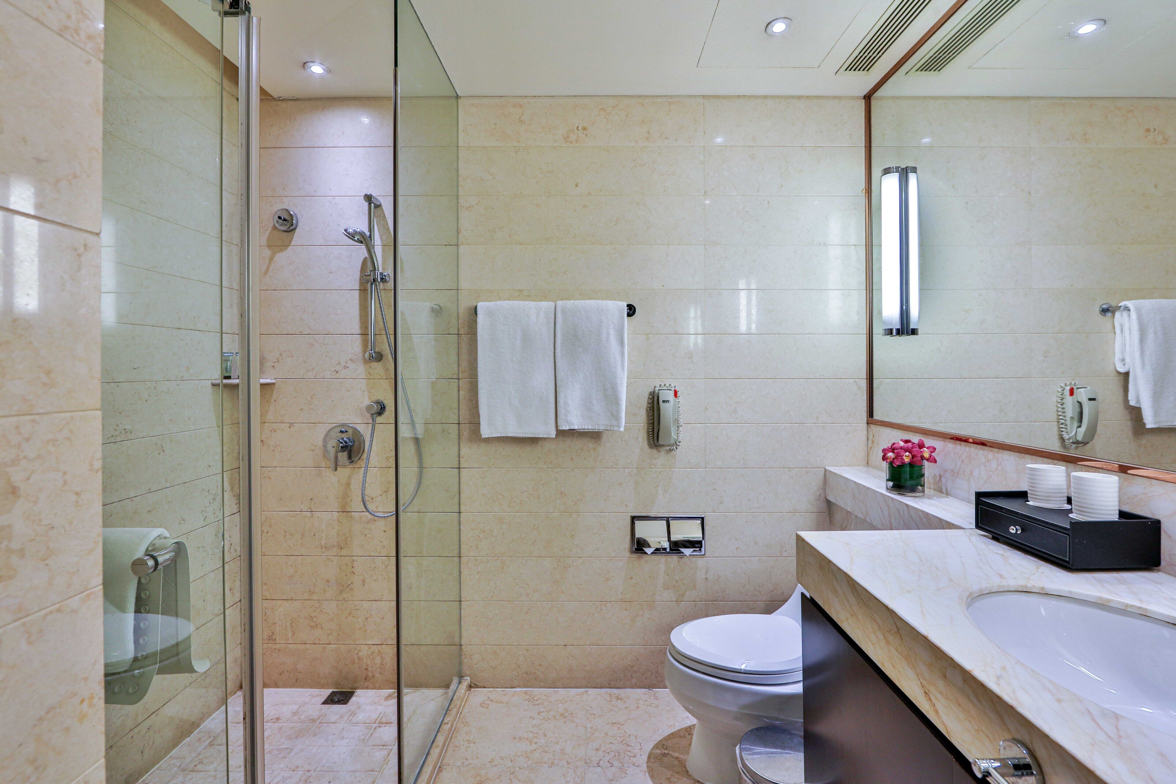Un bagno moderno con doccia vetrata, un water e un lavabo con piano in marmo.