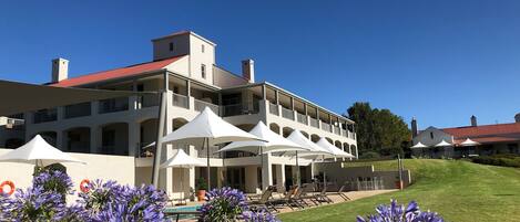 A multi-story hotel with balconies, outdoor seating, and a swimming pool.