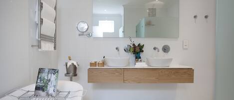 Un baño moderno con dos lavamanos, un espejo grande y un perchero para toallas.