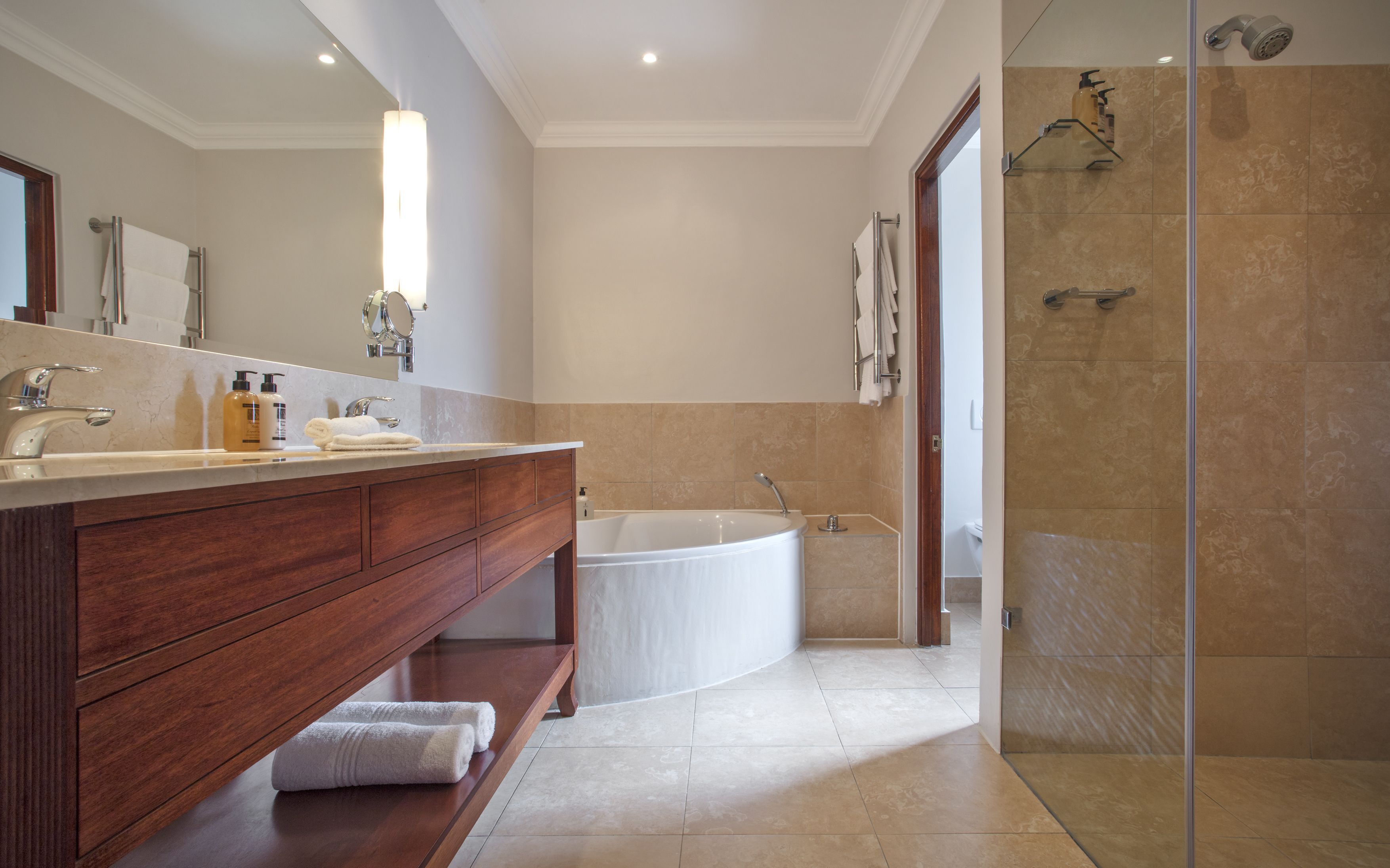 A modern bathroom with a freestanding bathtub, a glass-enclosed shower, and a vanity with a mirror and towel rack.