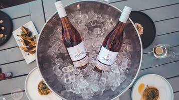 Dos botellas de vino Asara en un balde de hielo sobre una mesa con platos de comida.