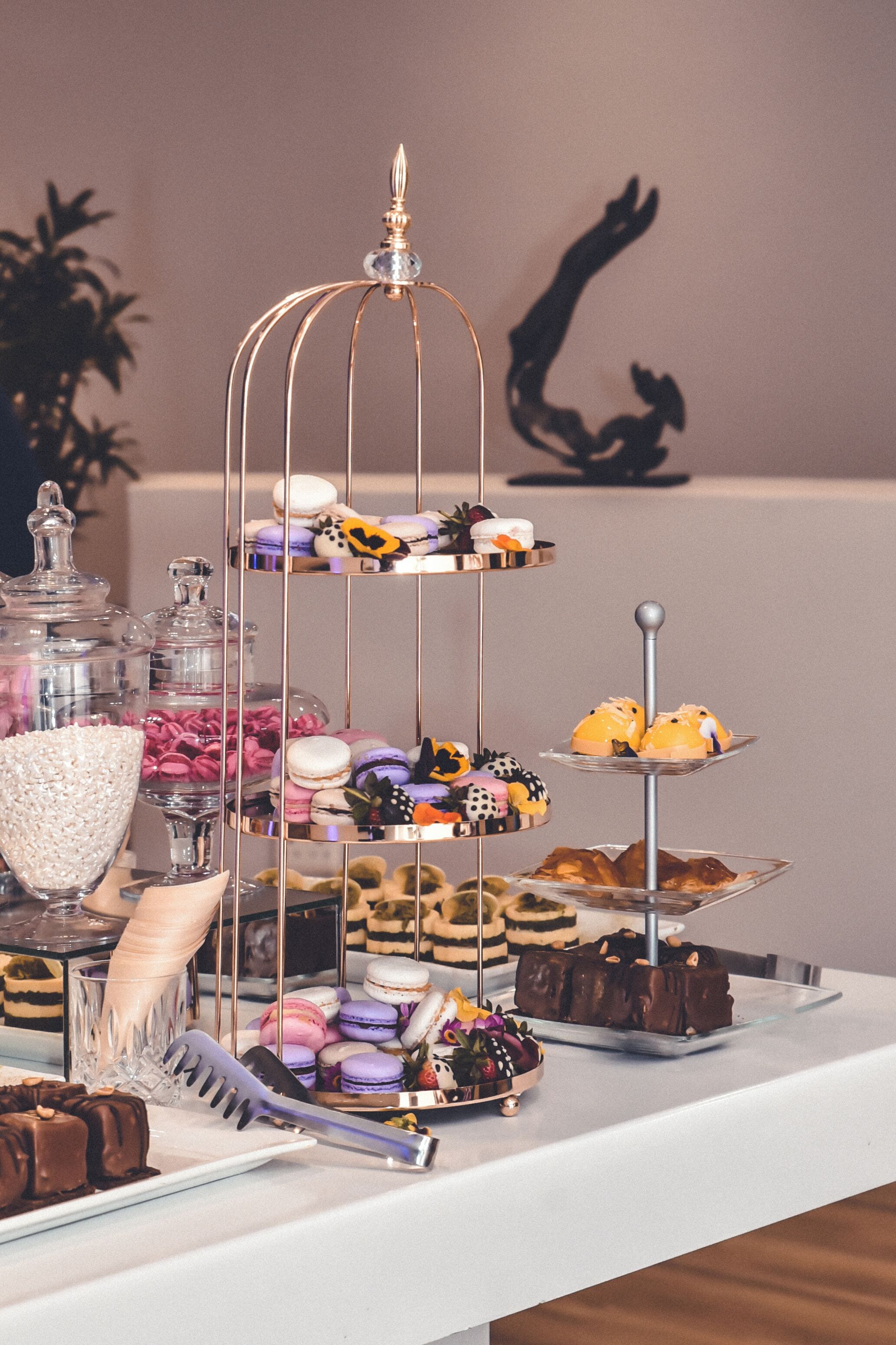 A dessert display with macarons, chocolates, and cookies on a white table.