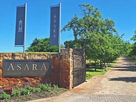 Un muro de piedra con un letrero que dice "ASARA WINE ESTATE" y dos banderines encima.