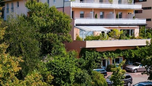 A multi-story residential building with balconies, surrounded by lush greenery. - Hotel Alpenblick Garni (Ueberlingen)