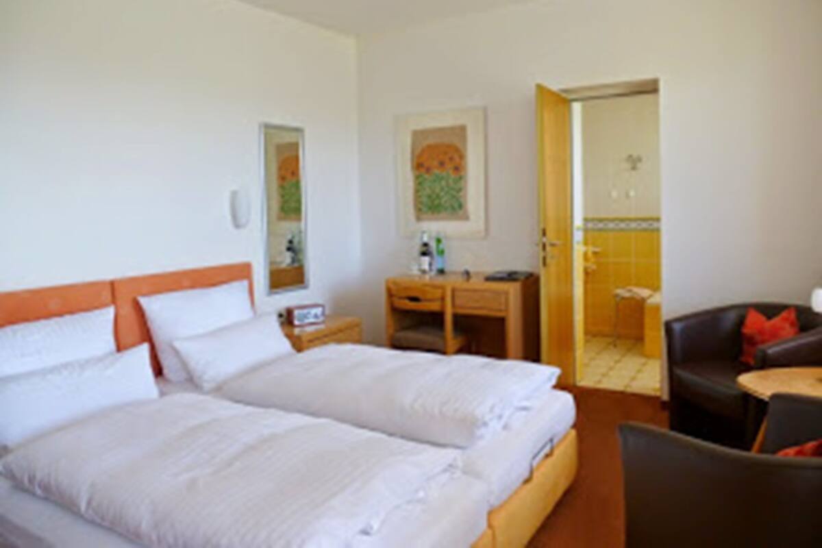 Una habitación de hotel con una cama doble, un escritorio, una silla y una mesita.