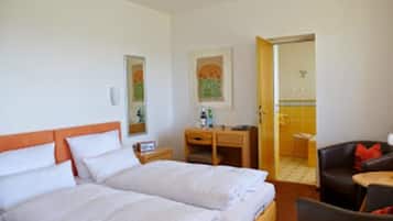 A hotel room with a double bed, a desk, a chair, and a small table.