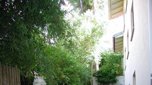 A garden with a statue, a wooden fence, and a small pond. - Hotel Alpenblick Garni (Ueberlingen)