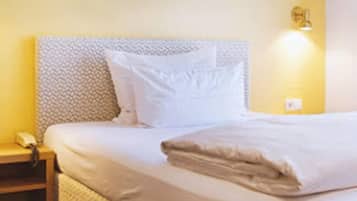Een net opgemaakt bed met witte lakens, een hoofdbord en een wanddecoratie.