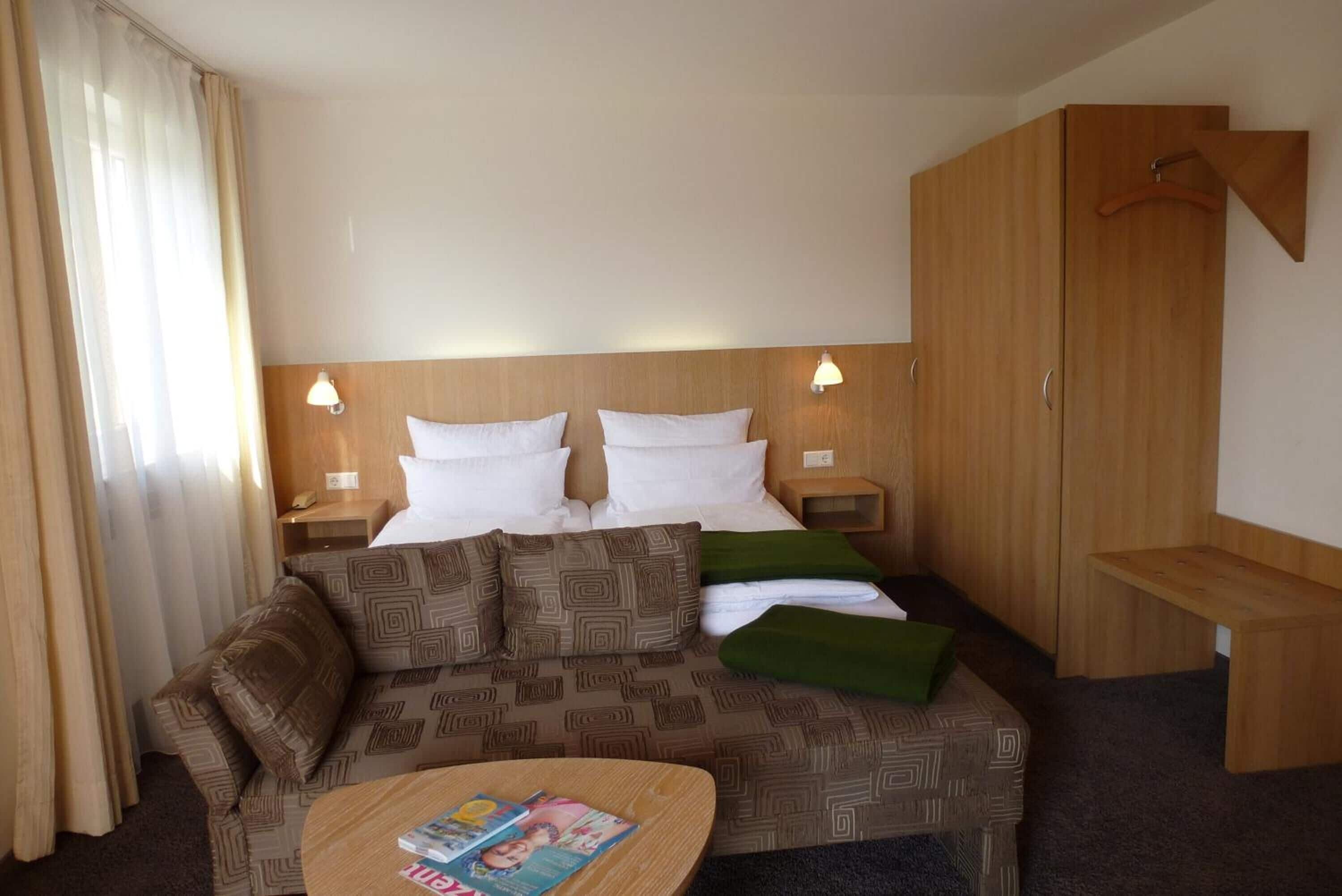 Ein Hotelzimmer mit einem Bett, einem Sofa, einem kleinen Tisch und einem Holzschrank.