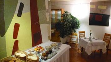 A dining area with a buffet table, chairs, and a large potted plant.