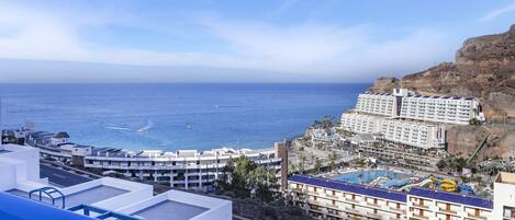 Un hotel frente al mar con varias construcciones, piscina y vistas al océano.