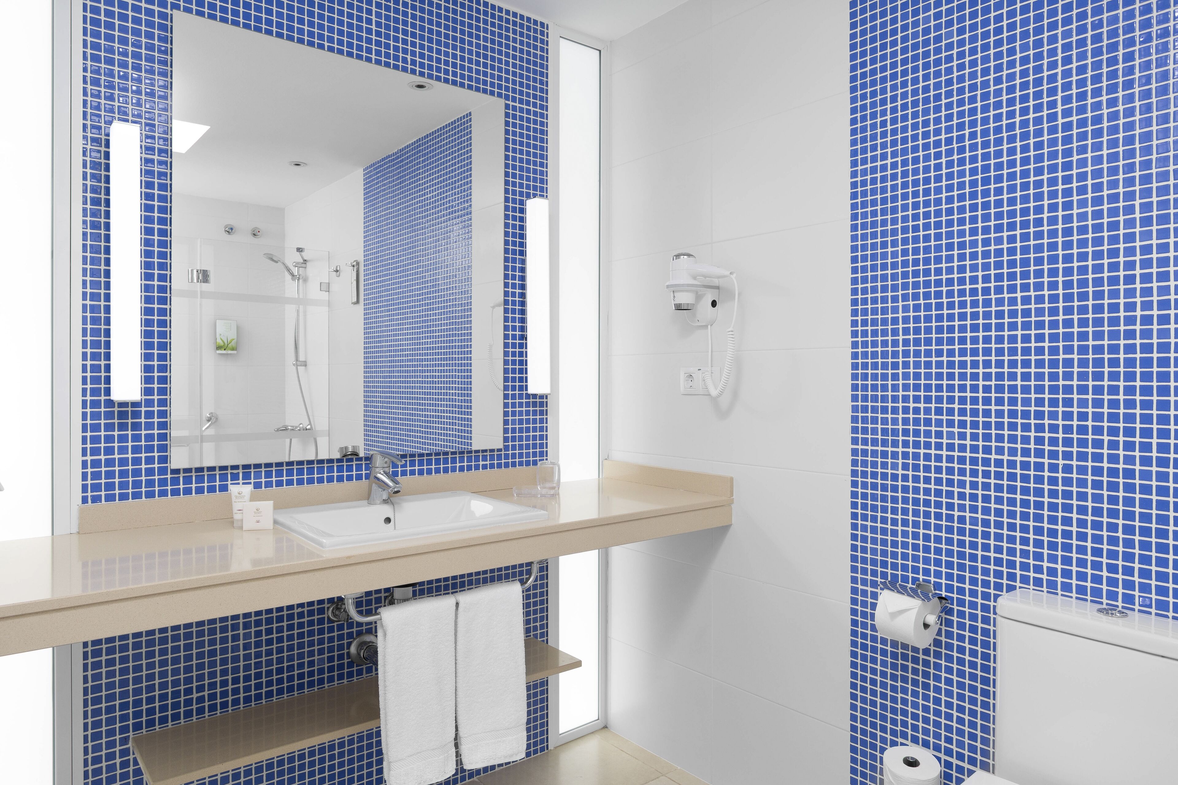 Ein Badezimmer mit Waschbecken, Spiegel und blauen Fliesen.