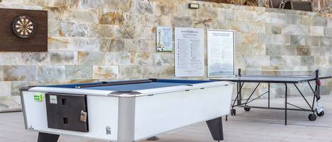 A pool table with a dartboard and a signboard in a stone-walled area.