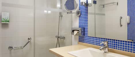 Un baño con cabina de ducha de vidrio, un lavamanos con espejo y paredes de azulejos azules.