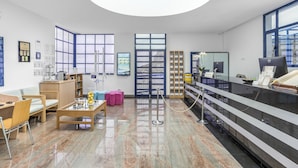 A reception area with a desk, chairs, a coffee table, a bookshelf, and a large window.