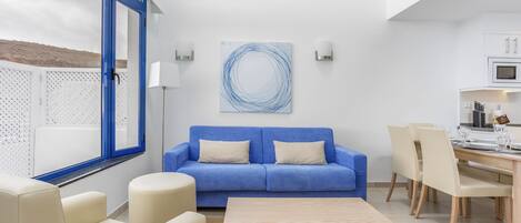 Una sala de estar moderna con un sofá azul, una mesa de centro de madera y un comedor con sillas y una mesa.