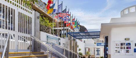 A hotel entrance with a staircase, multiple flags, and a 'Welcome' sign.