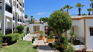 A courtyard with a cobblestone path, potted plants, and a palm tree. - Alfagar Cerro Malpique (Albufeira)