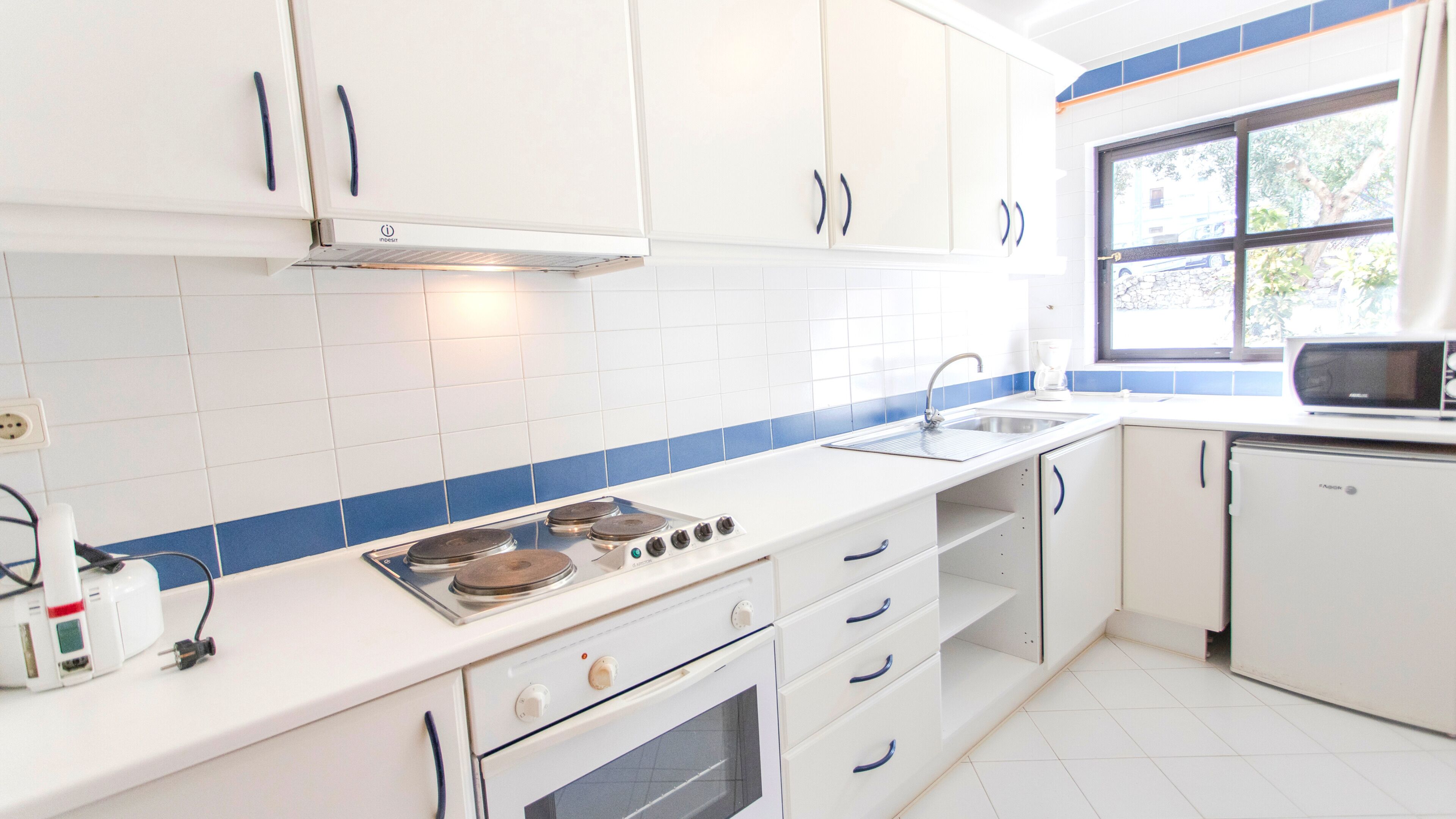 Een moderne keuken met witte kasten, een fornuis, oven en een magnetron.