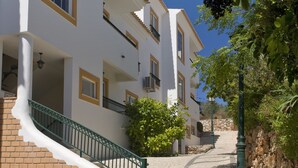 A multi-story building with a brick base and white upper floors, featuring balconies and a staircase leading to the upper levels. - Alfagar Cerro Malpique (Albufeira)