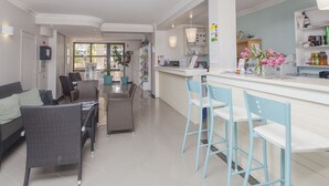 A modern kitchen with bar stools, a dining area with wicker chairs, and a bar counter with a vase of flowers. - Alfagar Cerro Malpique (Albufeira)