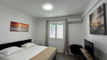 Een hotelkamer met een bed, een bureau, een stoel, een televisie, een schilderij en een raam.