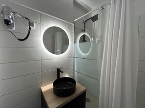 A bathroom with a round mirror, a hairdryer, and a sink with a basin.